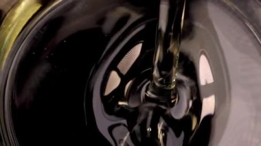 Sebze ayçiçeği ya da zeytinyağı siyah arka planda cam kaseye döküldü. Petrol tüketimi kavramının sağlık yararları. Yavaş çekim