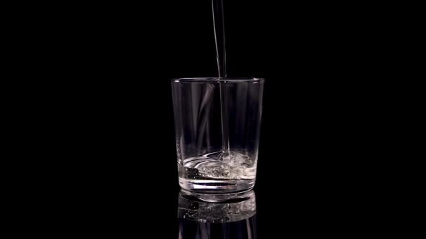 黒を背景にひまわりやオリーブオイルをグラスに注ぐ 石油消費の概念の健康上の利点 スローモーション — ストック動画