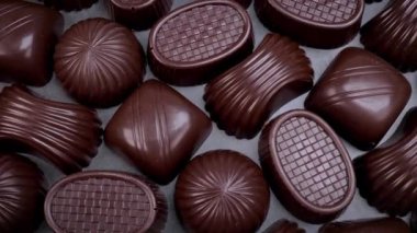 Dark chocolate assorted pralines on black background. Loving chocolate and sweets concept. Dolly shot 4k