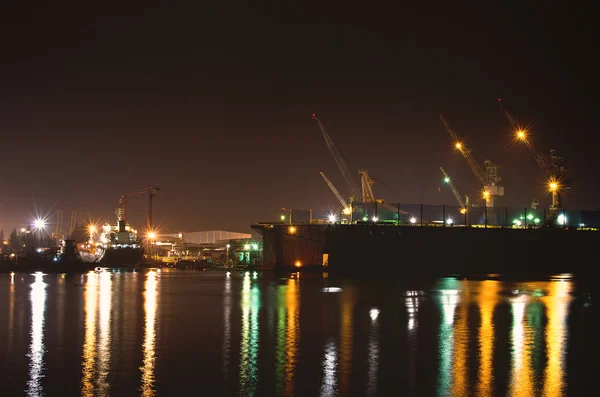 Vracht vrachtschip met kraan bridge in reparatie scheepswerf in de schemering — Stockfoto