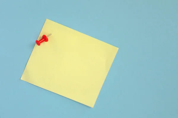 Hârtie galbenă cu pin pe fundal albastru — Fotografie, imagine de stoc