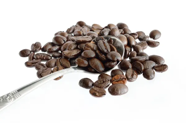 Kávová zrna a stříbrnou lžičkou izolované na bílém — Stock fotografie