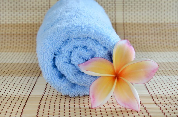Blauwe handdoek en plumeria bloem op houten achtergrond — Stockfoto