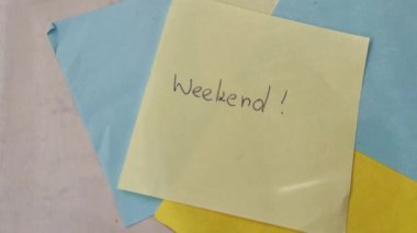 Sticky note with WEEKEND word. WEEKEND message concept with magnifier
