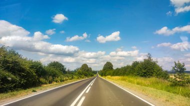 Asphalt road at the summer time. Blue sky with clouds. Travel and transportation concept.