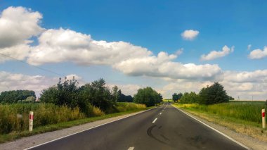 Asphalt road at the summer time. Blue sky with clouds. Travel and transportation concept.