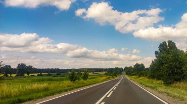 Asphalt road at the summer time. Blue sky with clouds. Travel and transportation concept.