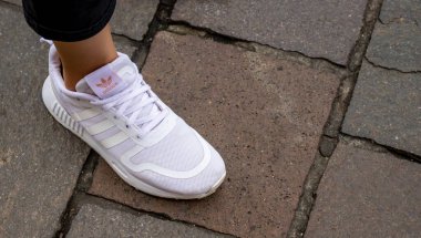 Varşova Polonya, 2 Ekim 2022: beyaz Adidas ayakkabıları giyen ayaklar. Kız bacakları beyaz spor ayakkabı giyiyor. Adidas beyaz ayakkabı giyen kadınlar