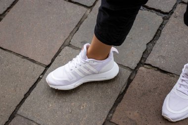 Varşova Polonya, 2 Ekim 2022: beyaz Adidas ayakkabıları giyen ayaklar. Kız bacakları beyaz spor ayakkabı giyiyor. Adidas beyaz ayakkabı giyen kadınlar