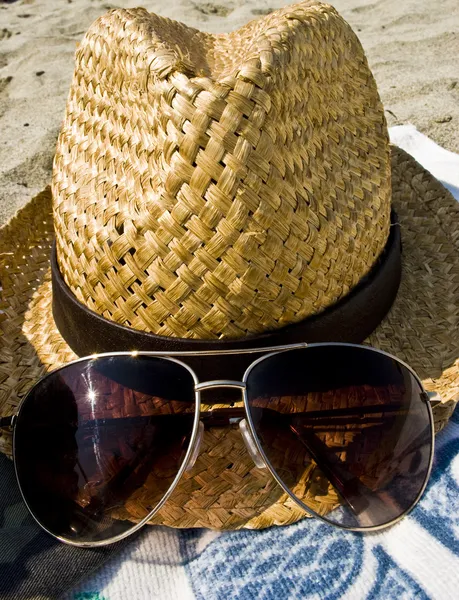 Hatt och solglasögon på stranden. — Stockfoto