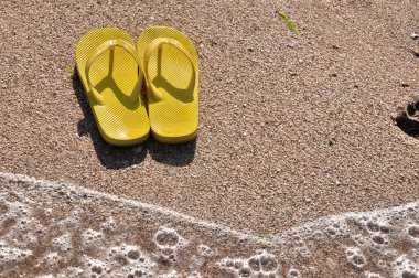 plaj kum üzerine sarı flip flop