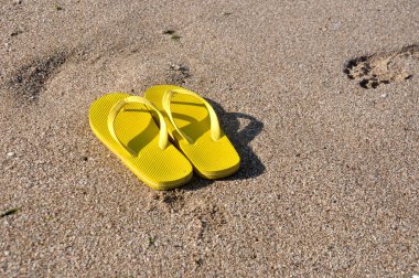 plaj kum üzerine sarı flip flop