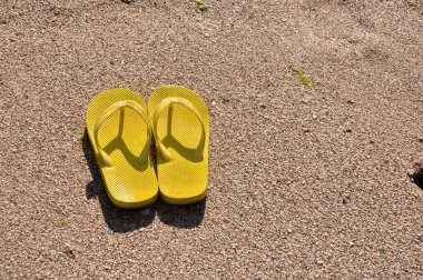 plaj kum üzerine sarı flip flop