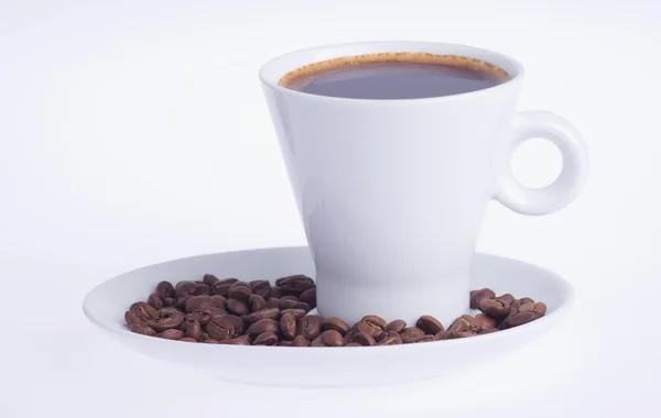 Coffee in a cup on a saucer covered with coffee beans — Stock Photo, Image