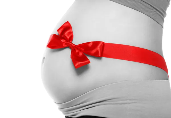 Belly of a pregnant woman tied with a red bow — Stock Photo, Image