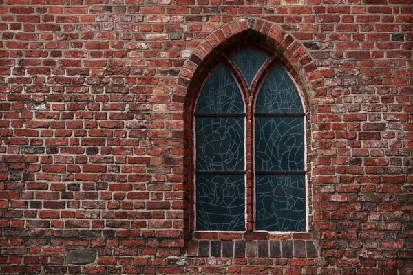 Parede de tijolo gótico com uma janela, uma janela de vidro manchado — Fotografia de Stock