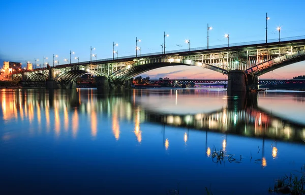 Bakgrundsbelyst bron på natten och återspeglas i vattnet — Stockfoto