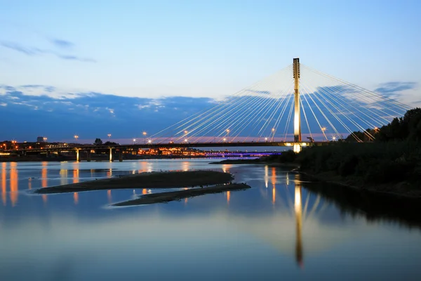 Puente colgante por la noche y reflejado en el agua — Foto de Stock
