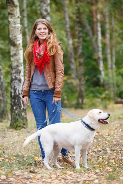 Mooie vrouw wandelen met haar hond in het bos — Stockfoto