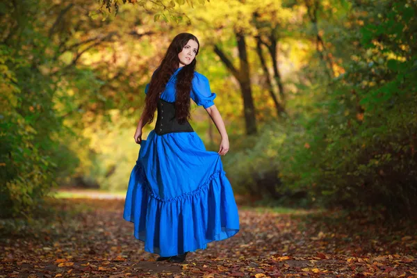 Una hermosa mujer en un vestido azul en el parque de otoño — Foto de Stock