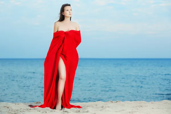 Mooie vrouw in het rood op het strand — Stockfoto