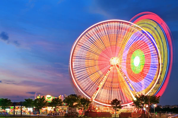 Parque de diversões ao entardecer - Roda gigante em movimento — Fotografia de Stock