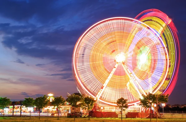 Parque de atracciones al anochecer - Rueda de la fortuna en movimiento —  Fotos de Stock