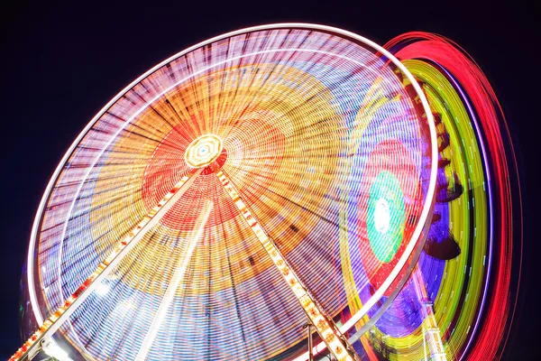 Парк развлечений ночью - колесо обозрения в движении — стоковое фото