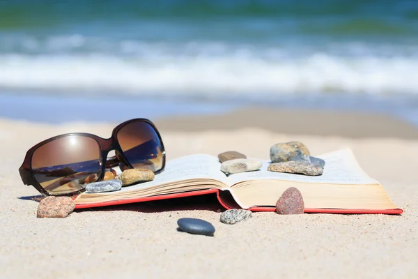 Boek en zon bril op het strand — Stockfoto