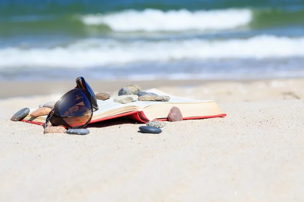 Boek en zon bril op het strand — Stockfoto