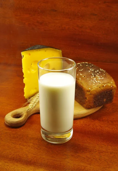 Bild av ett glas mjölk, bröd på bordet, spike och ost — Stockfoto