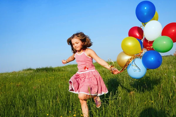 Glückliches kleines Mädchen, das mit Luftballons ins Freie springt — Stockfoto