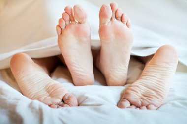 ? ouple ayaklar altında bir yorgan yatakta