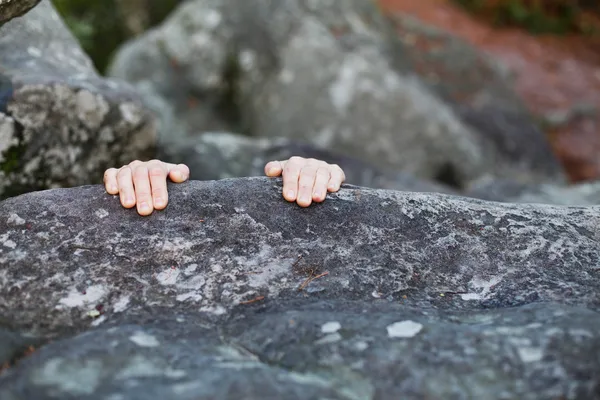 Handen vastklampen aan de rand van een stenen klif — Stockfoto