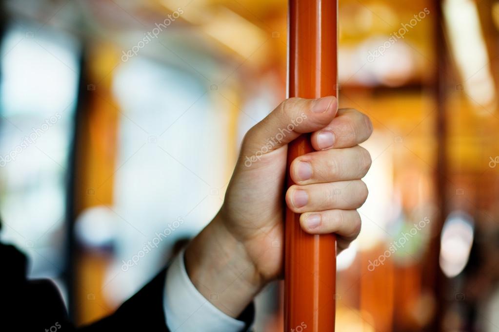 Hand holds handrail in public transport
