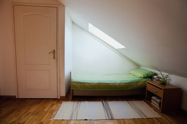 Кровать с тумбочкой под окном — стоковое фото
