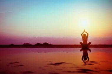 Silhouette of young woman practicing yoga clipart