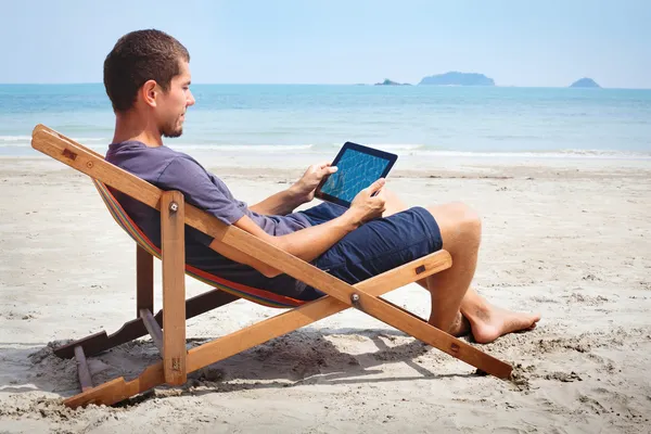 Homem trabalhando com tablet na praia — Fotografia de Stock