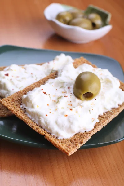 Snack of rye crisps witn spicy cream cheese and olives — Stock Photo, Image