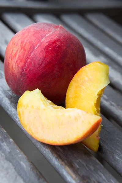 Peach with its slices on a wooden table — Stock Photo, Image