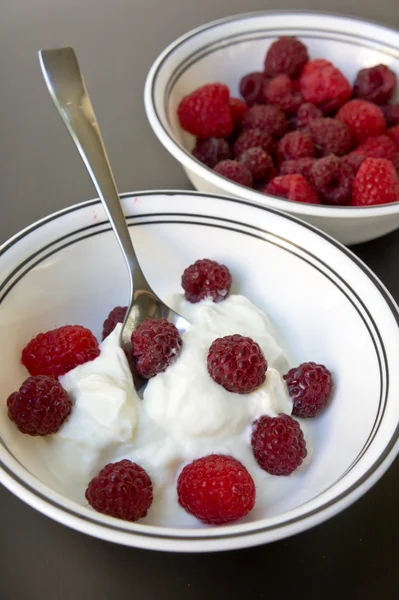 A bowl of raspberries on a black wooden table closeup — Stock Photo, Image