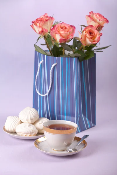 A cup of tea with white souffle and roses in present bag — Stock Photo, Image