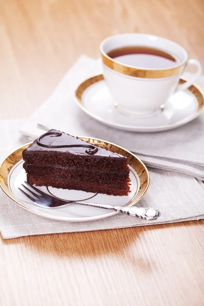 Tranche de gâteau au chocolat avec une tasse de thé servi sur une table — Photo