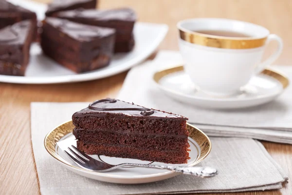 Tranche de gâteau au chocolat avec une tasse de thé servi sur une table — Photo