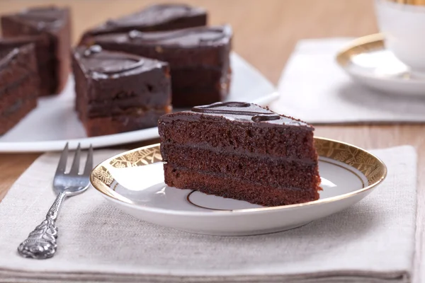 Rebanada de pastel de chocolate con una taza de té servido en una mesa —  Fotos de Stock