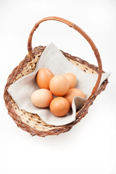 Huevos marrones en una cesta sobre una servilleta de lino sobre fondo blanco —  Fotos de Stock