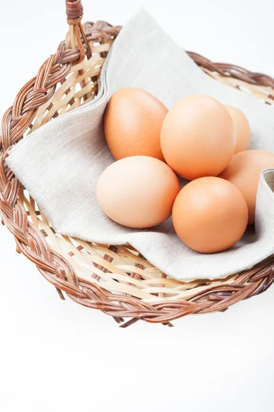 Brown eggs in a basket on a linen napkin on white background — Stock Photo, Image