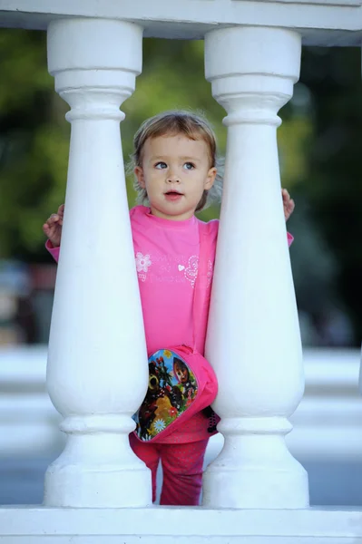 Kleine meisje kijkt door het hek — Stockfoto