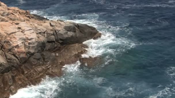 Ola de mar rompiendo en la costa rocosa con mucha espuma — Vídeo de stock