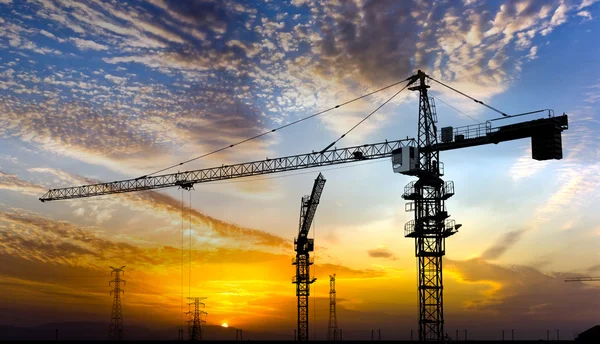 Industriële bouwkranen en silhouetten boven de zon bij zonsopgang. — Stockfoto